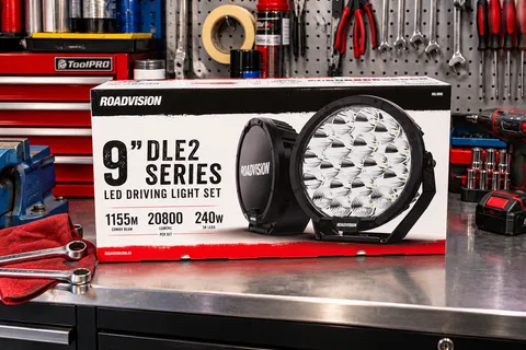 Roadvision 9 inch DLE2 Series LED driving light set in its retail box on a workshop bench, with the round LED light and its cover visible on the box